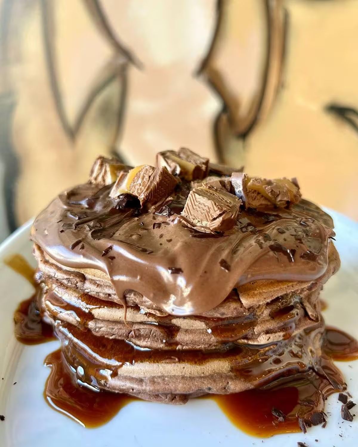 Pila di pancake al cioccolato ricoperti di salsa al cioccolato e caramelle tritate.