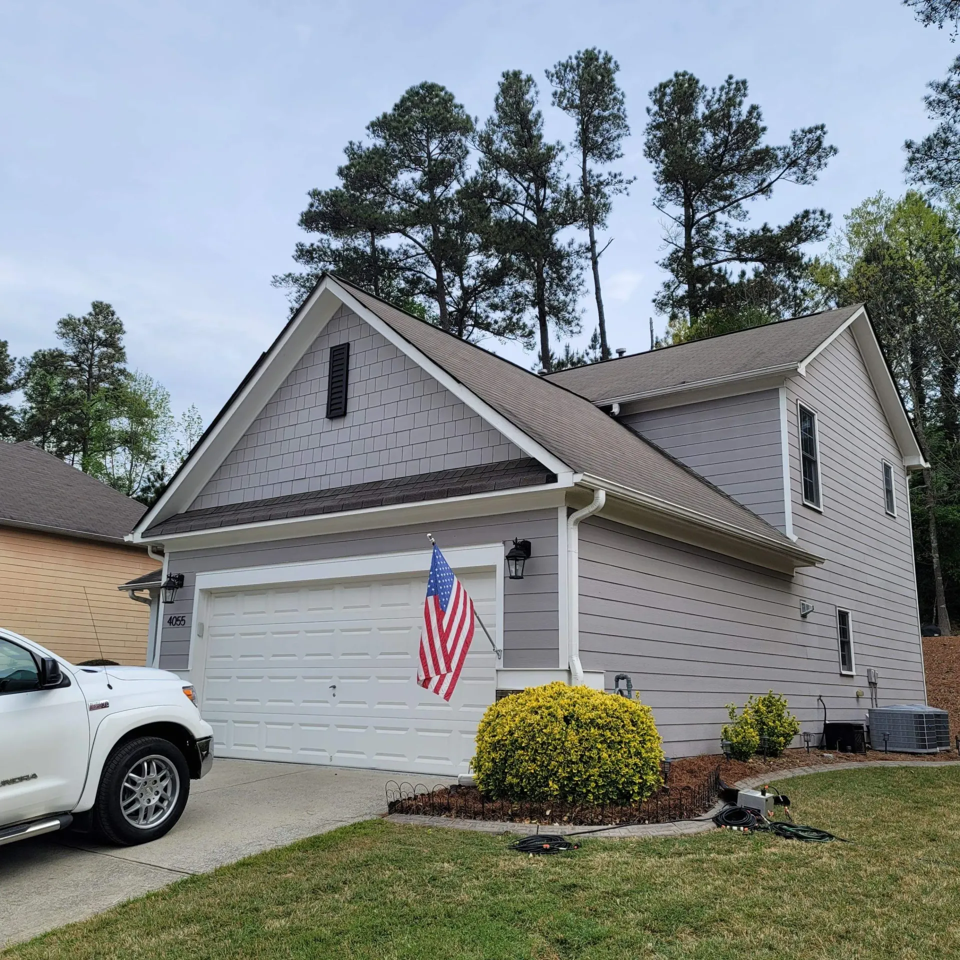 Gray house with white garage door, American flag, and a white truck.