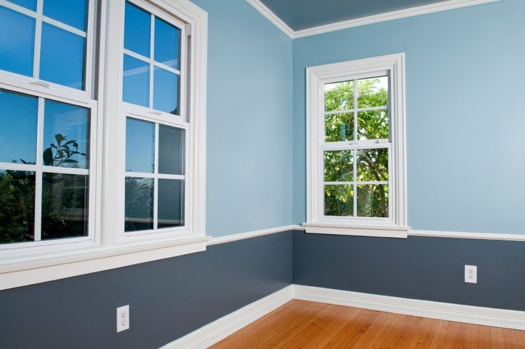 Empty room with blue walls, white trim, and windows; wood floor.