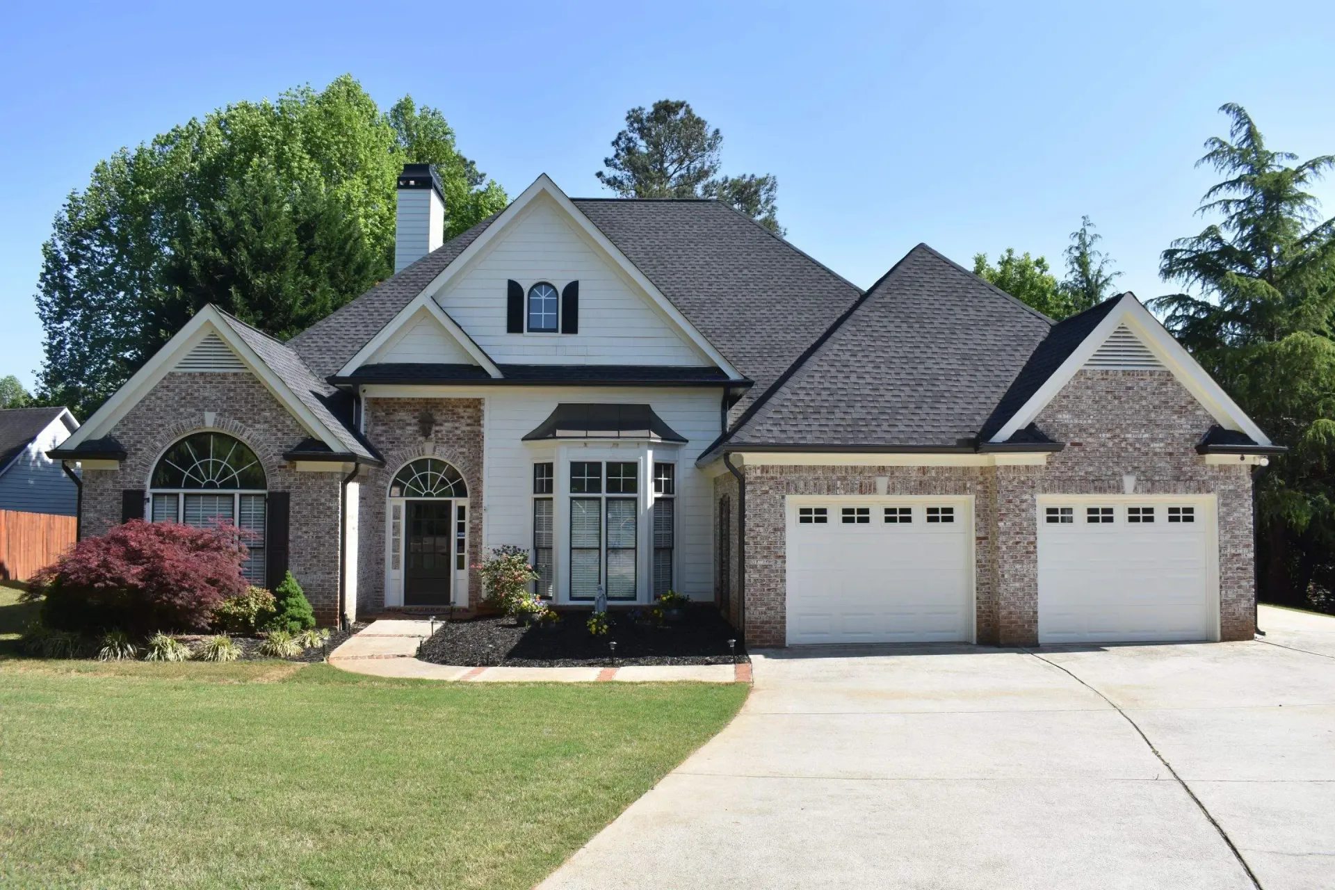A two-story house with a brick exterior and white trim on a sunny day.