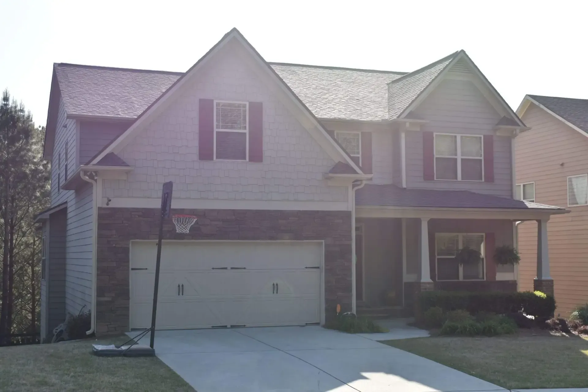 Two-story house with a gray exterior, a garage, a basketball hoop, and a covered porch.