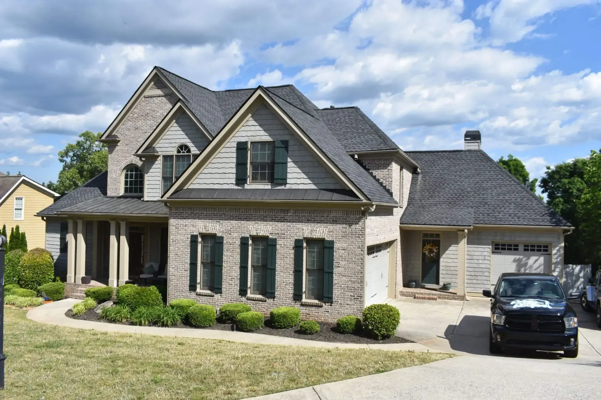 Two-story brick house with a dark roof and a car parked in the driveway.
