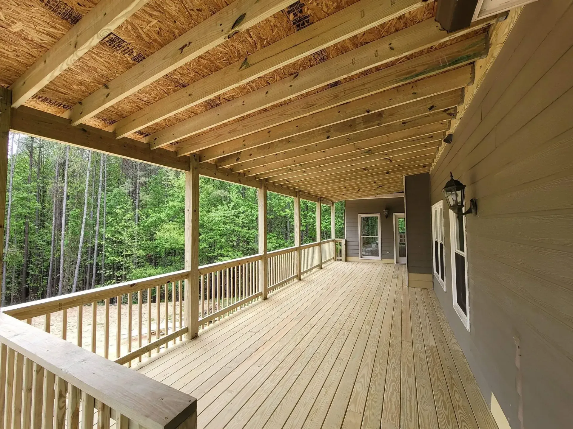 Wooden porch with railing, overlooking a forest, brown tones.