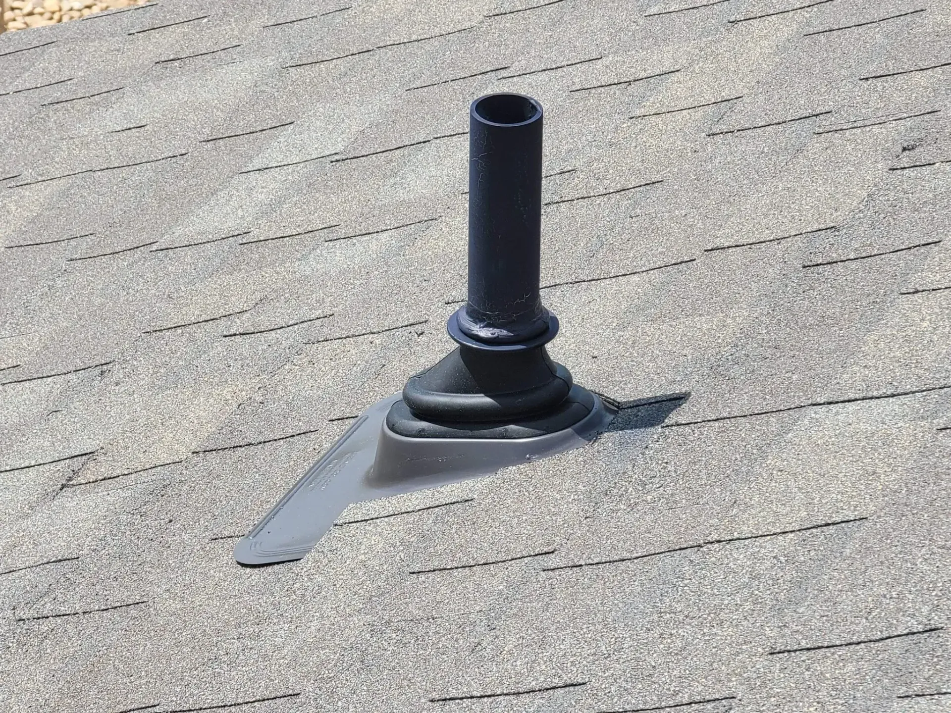 Black plumbing vent pipe on gray asphalt shingle roof.