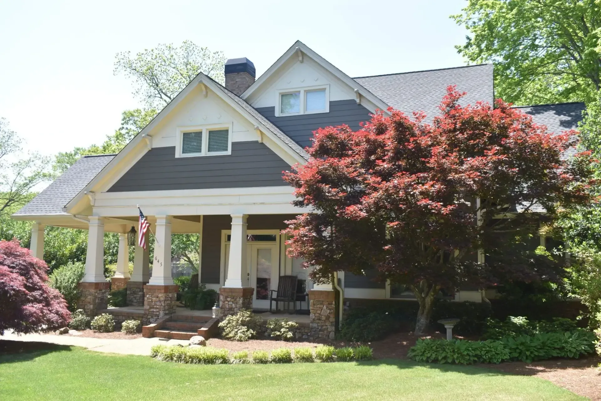 Craftsman-style house with porch, gray roof, white trim, and red Japanese maple tree in front.