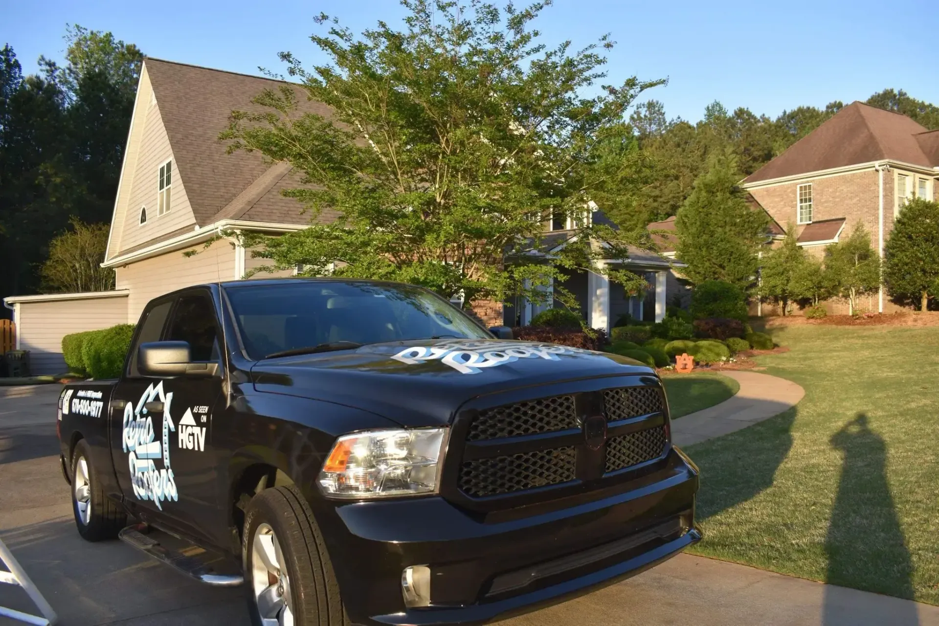 Black pickup truck parked in front of a house on a sunny day.
