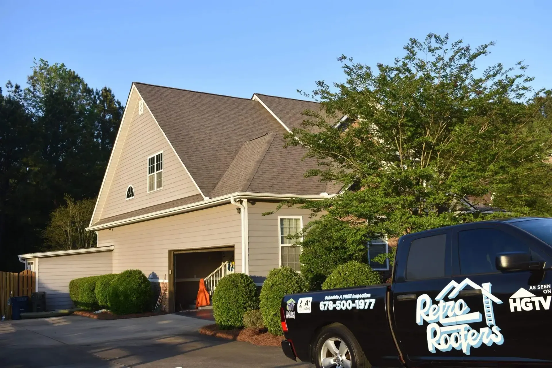 A light tan house with a brown roof, parked black truck with 