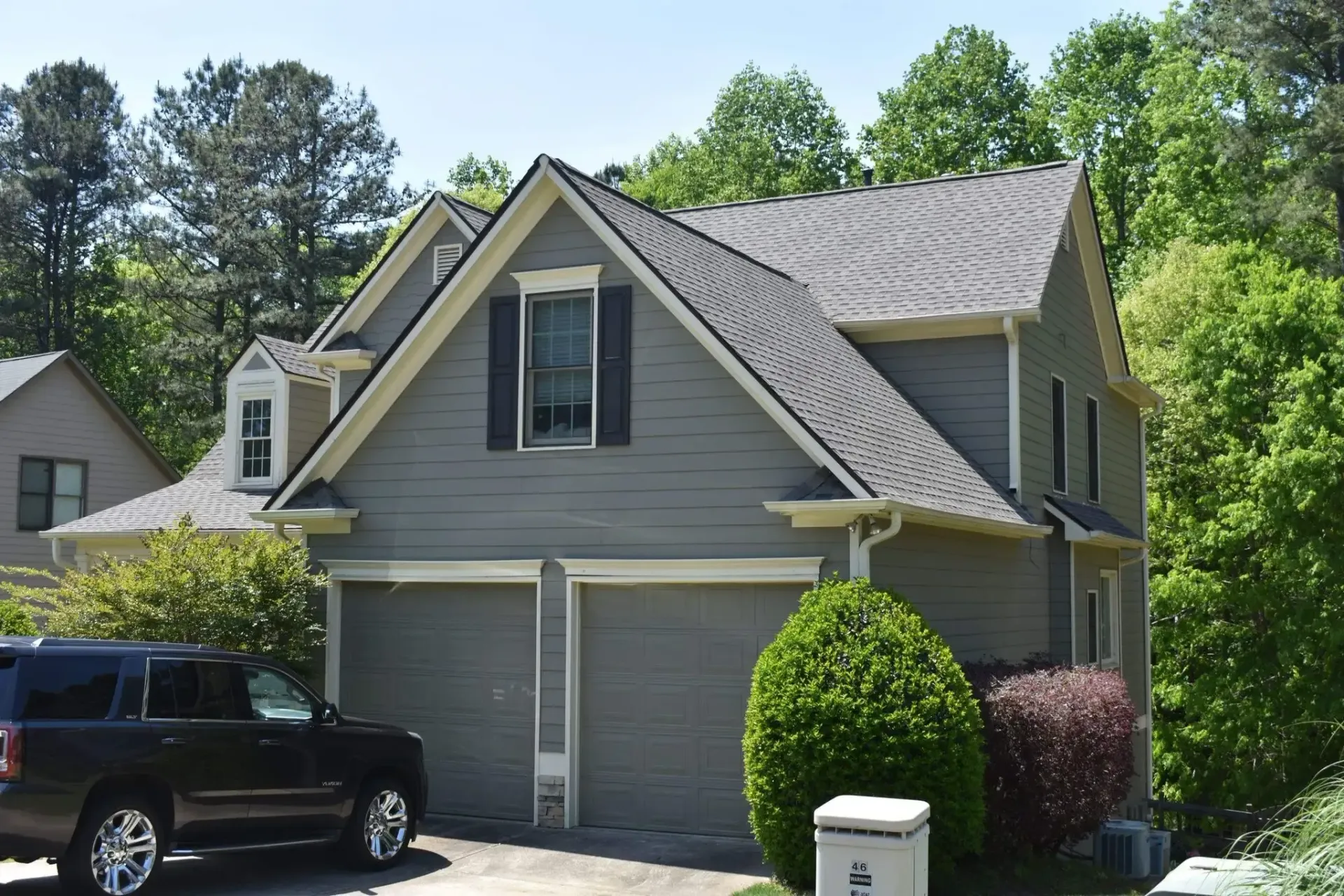 Two-story gray house with a black SUV parked in the driveway.