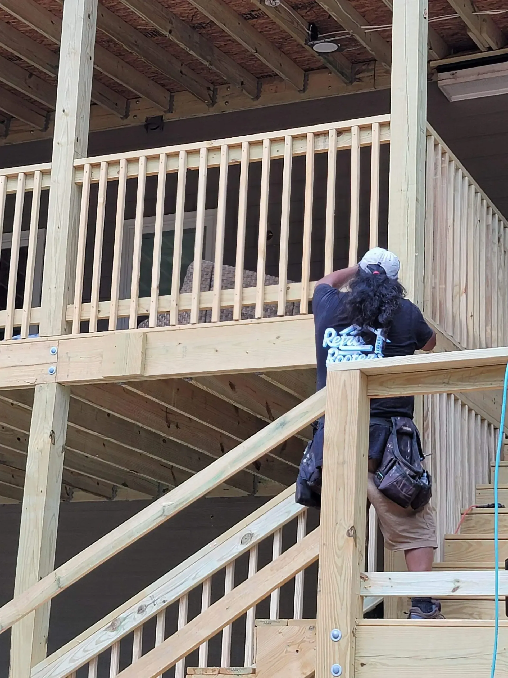 Person on a wooden deck with stairs, looking at the second level.