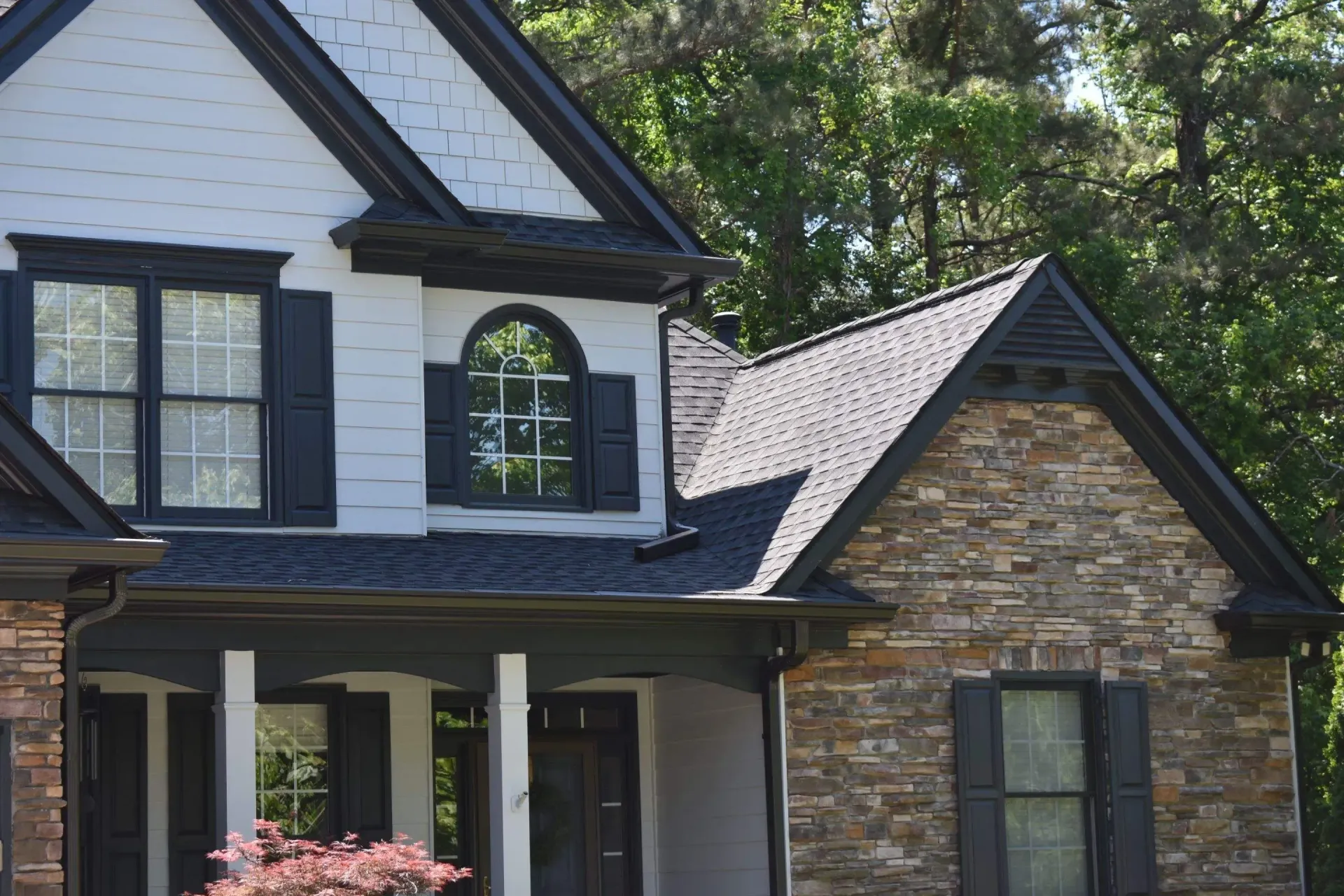 A two-story house with a stone and white exterior, dark trim, and shutters.