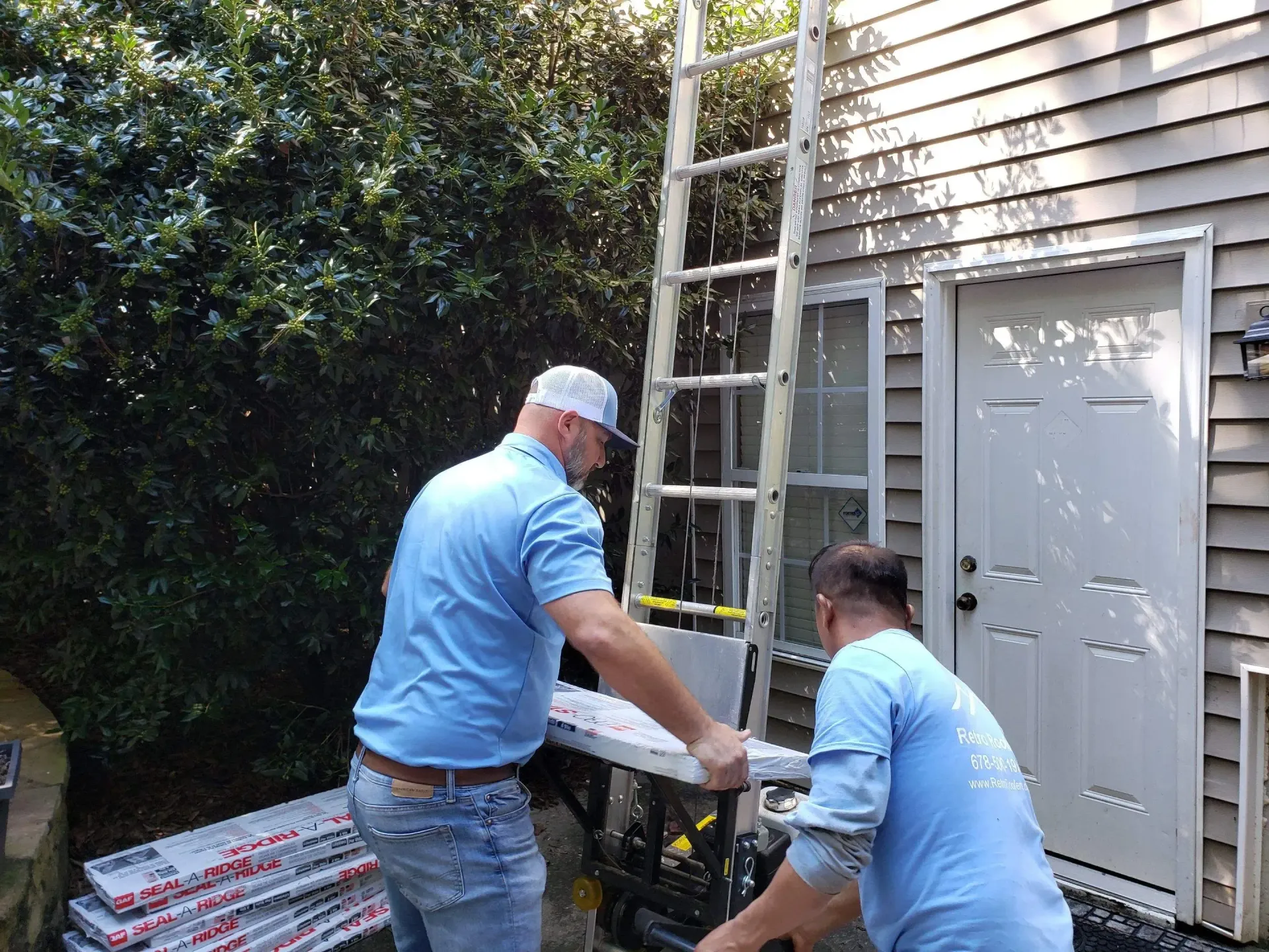 Two men near a house, loading a saw, with a ladder against the wall, preparing construction work.