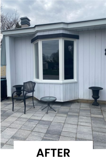 A picture of a house with a bay window and a chair and table