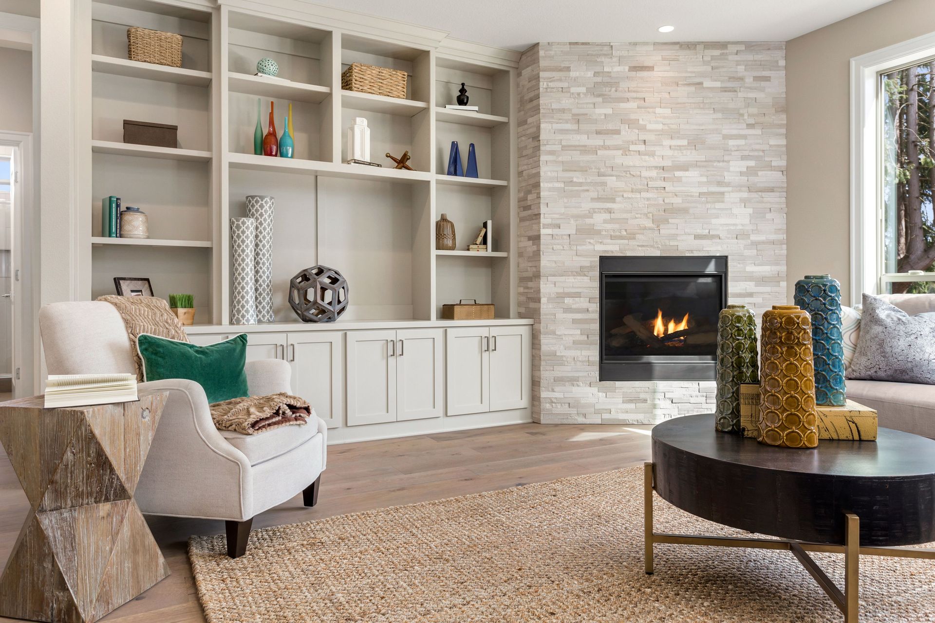 Cozy living room with built-in shelves, stone fireplace, armchair, and round coffee table.