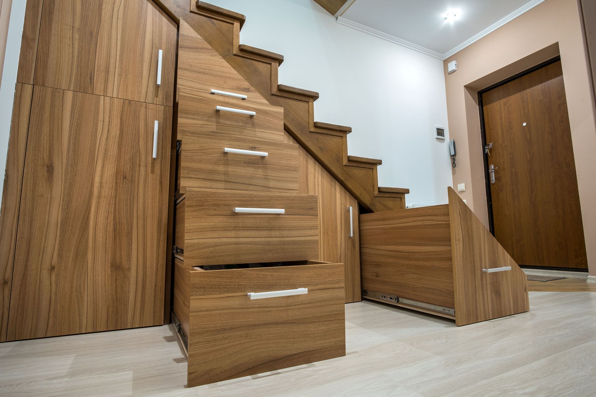 Wooden staircase with built-in storage drawers in a modern hallway.