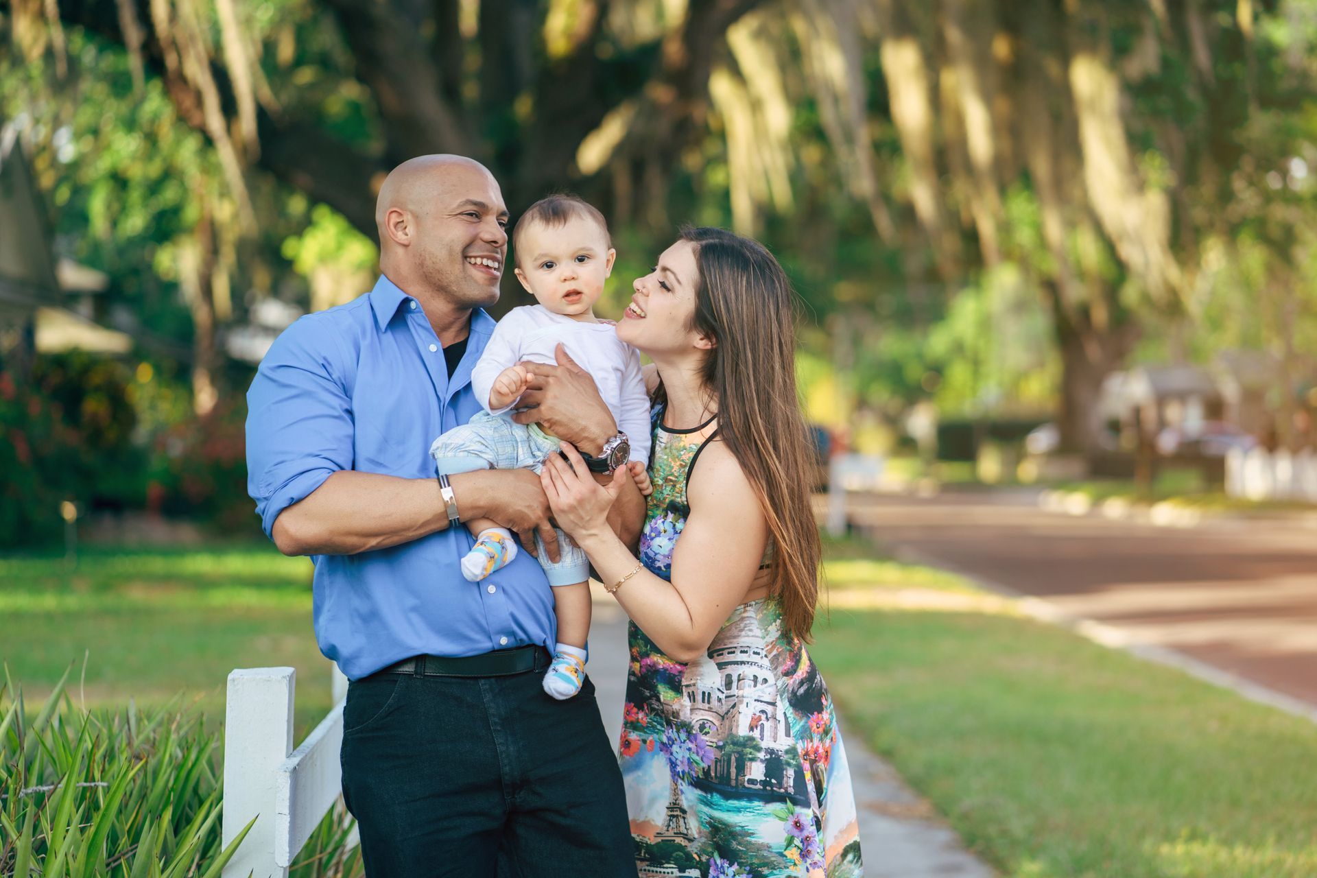 Sandhill crane with chick, near water. Crane has a red head and the chick is fluffy and tan.