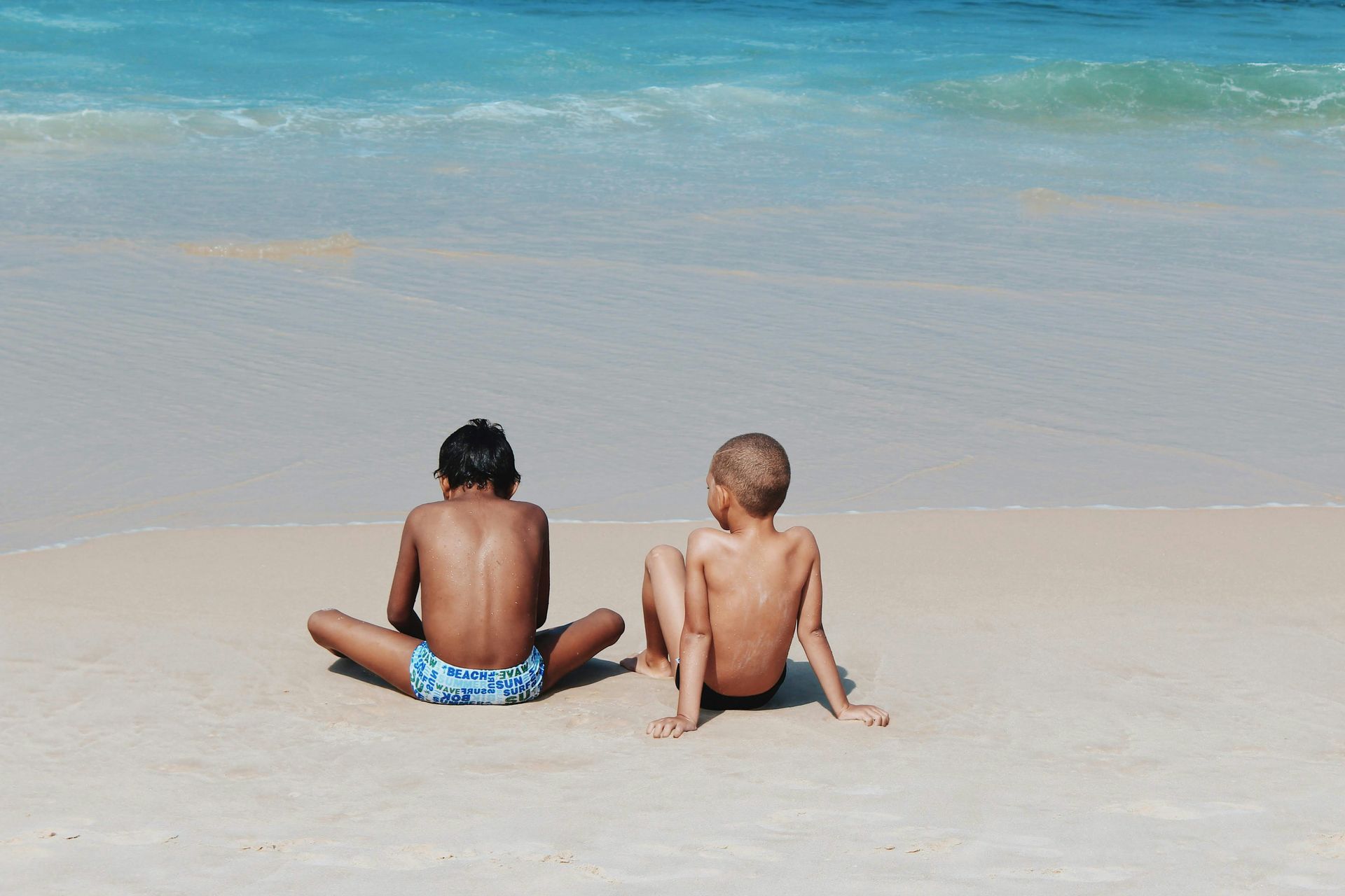 Woman holding a baby, both looking at the camera. Baby holds a flower, overlooking a cloudy ocean.