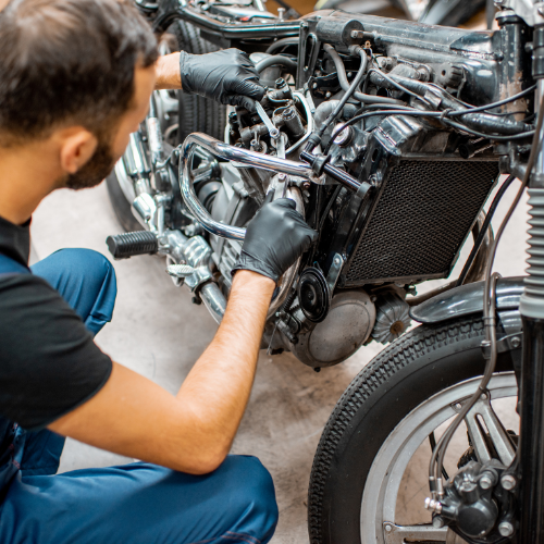 A man is working on a motorcycle with a wrench.