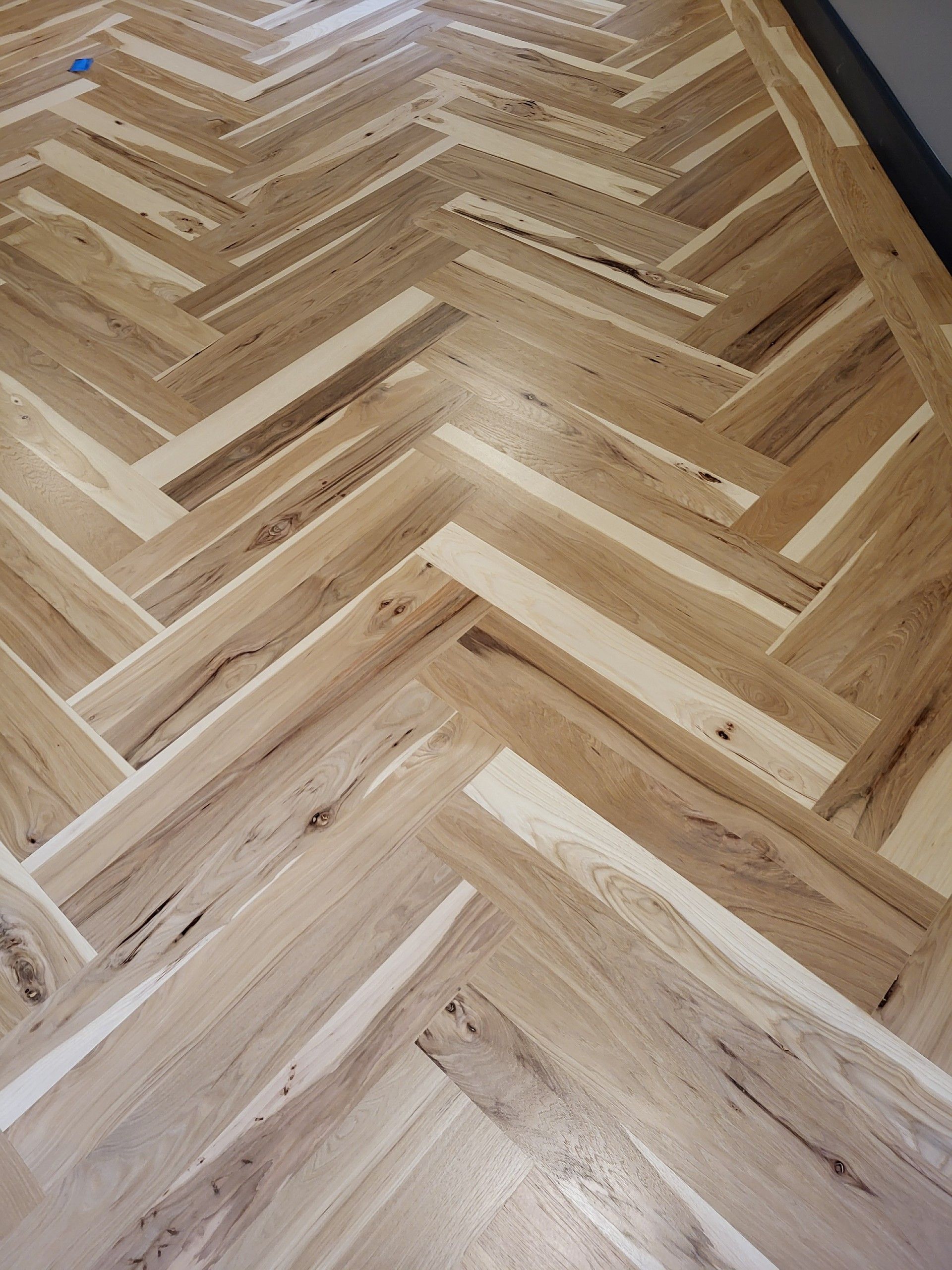 Light-colored hardwood flooring installed in a herringbone pattern with natural wood grain and tonal variations.