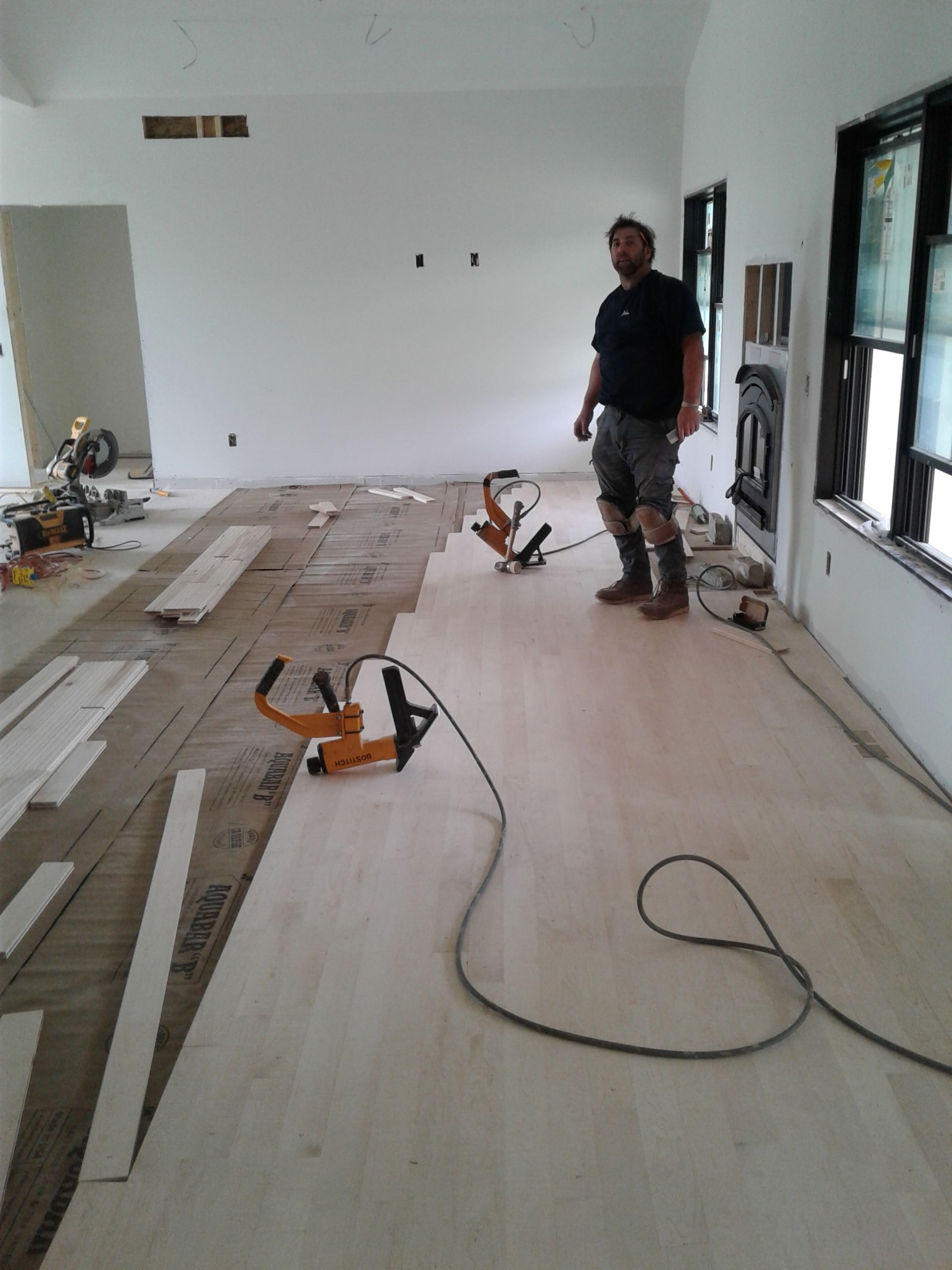 A fireplace with a multicolored mosaic tile surround and a cardboard cover over the opening, set above a wood floor.