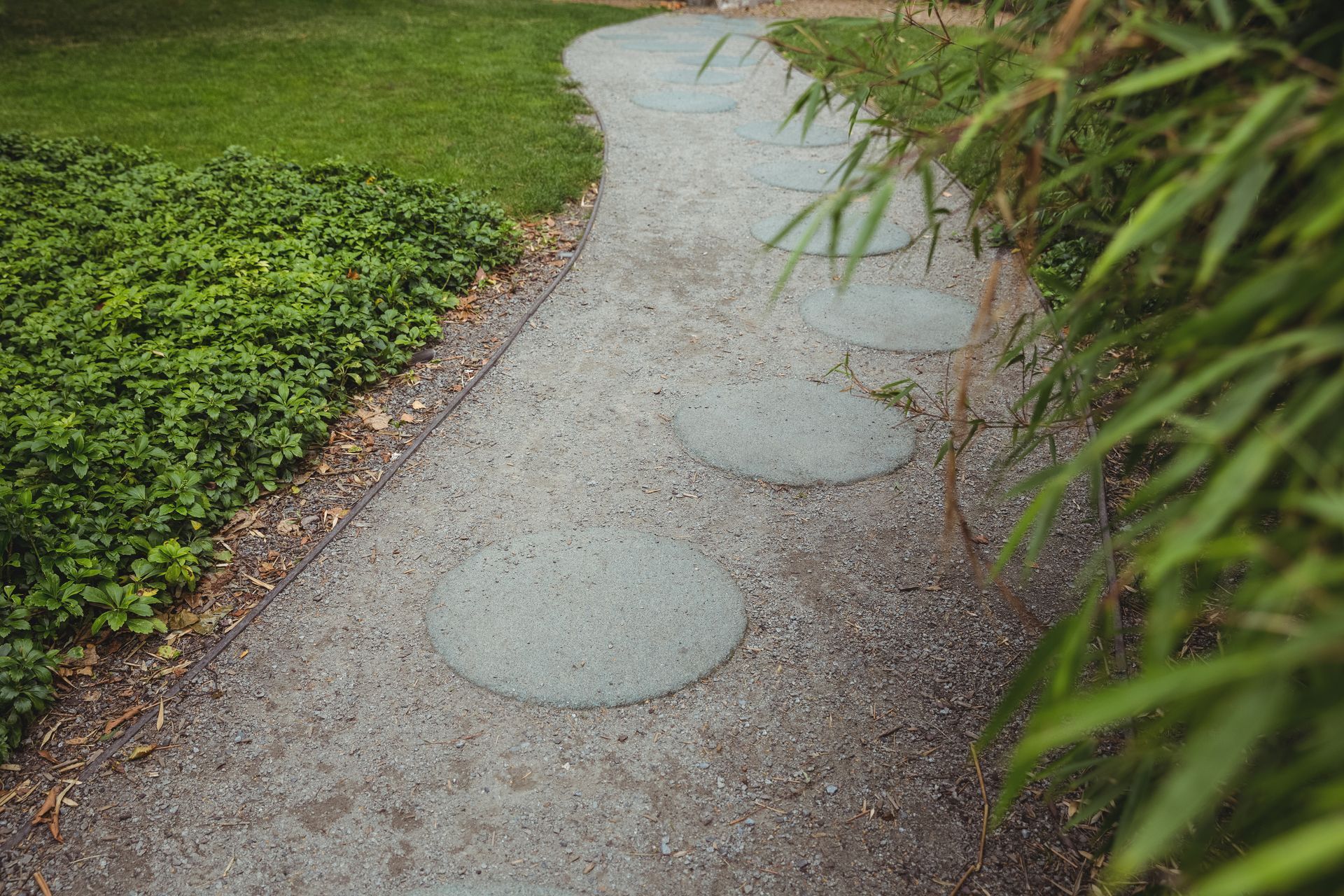 A gravel path with stepping stones in the middle of a garden.