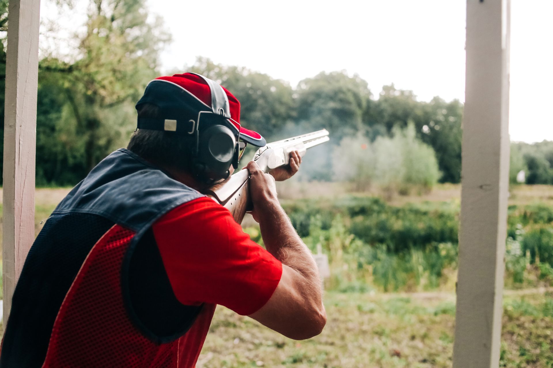 Hunter shoots with a shotgun on a target in special clothes and headphones