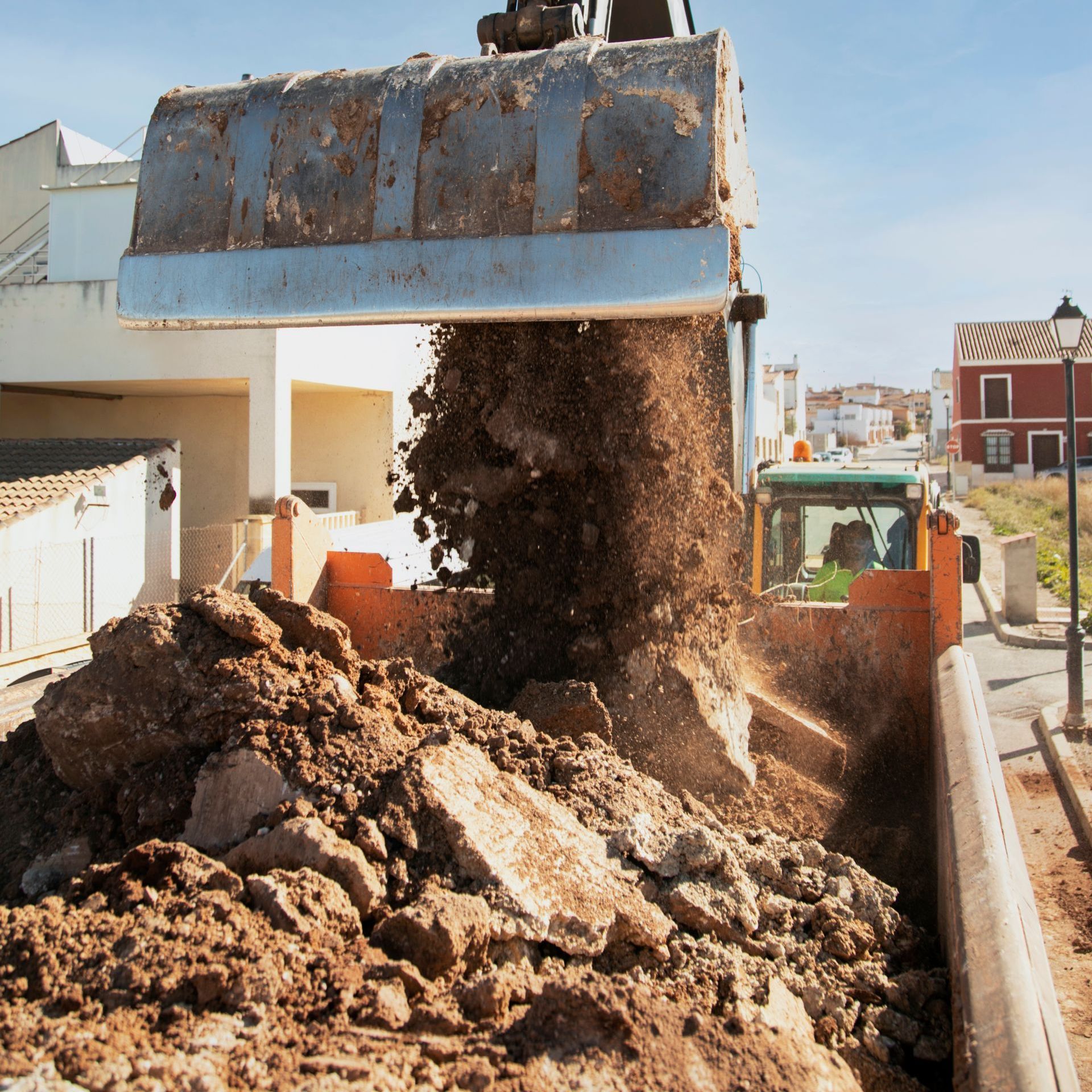 A large pile of dirt is being dumped into a truck