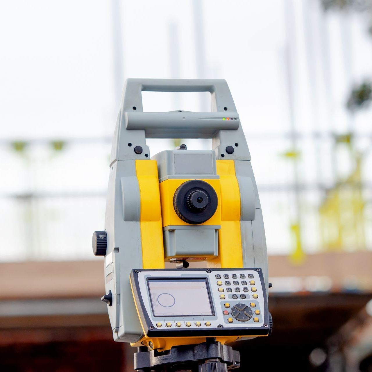 A yellow and gray theodolite is sitting on a tripod