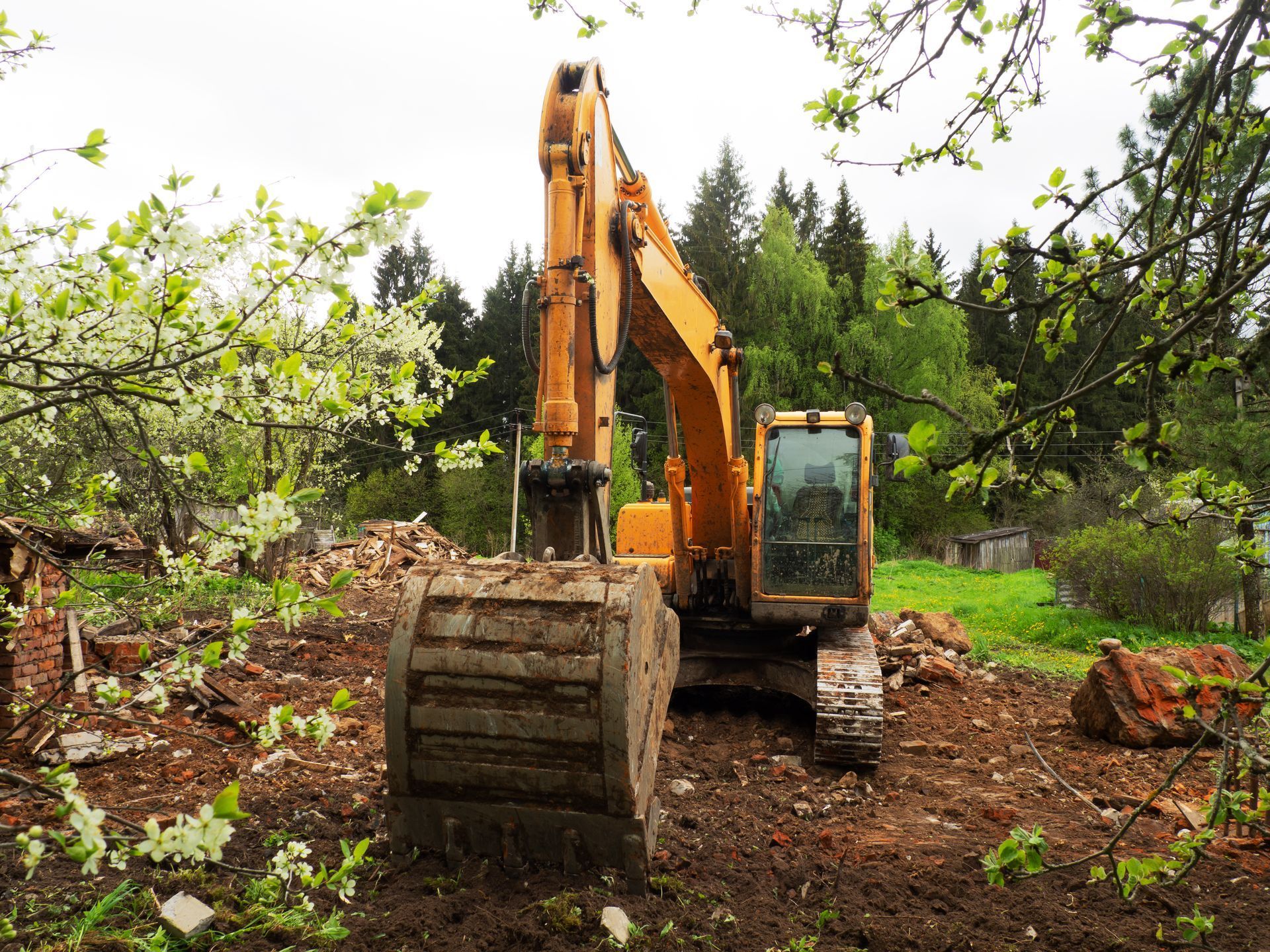 A yellow excavator is sitting on top of a dirt field.