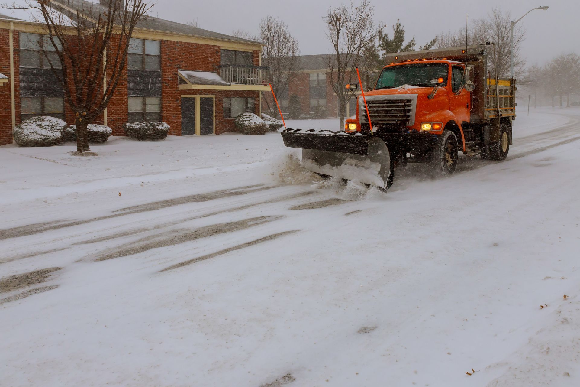 A snow plow is driving down a snowy street.