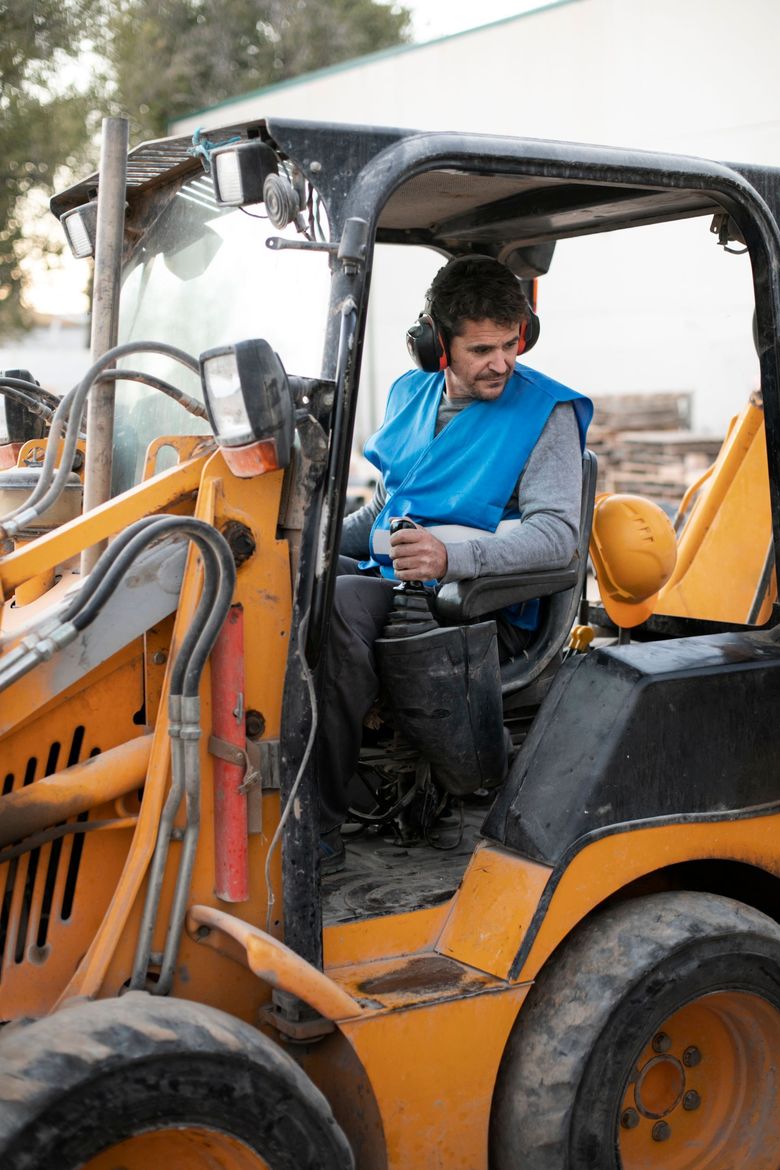 A man is sitting in the driver 's seat of a construction vehicle.