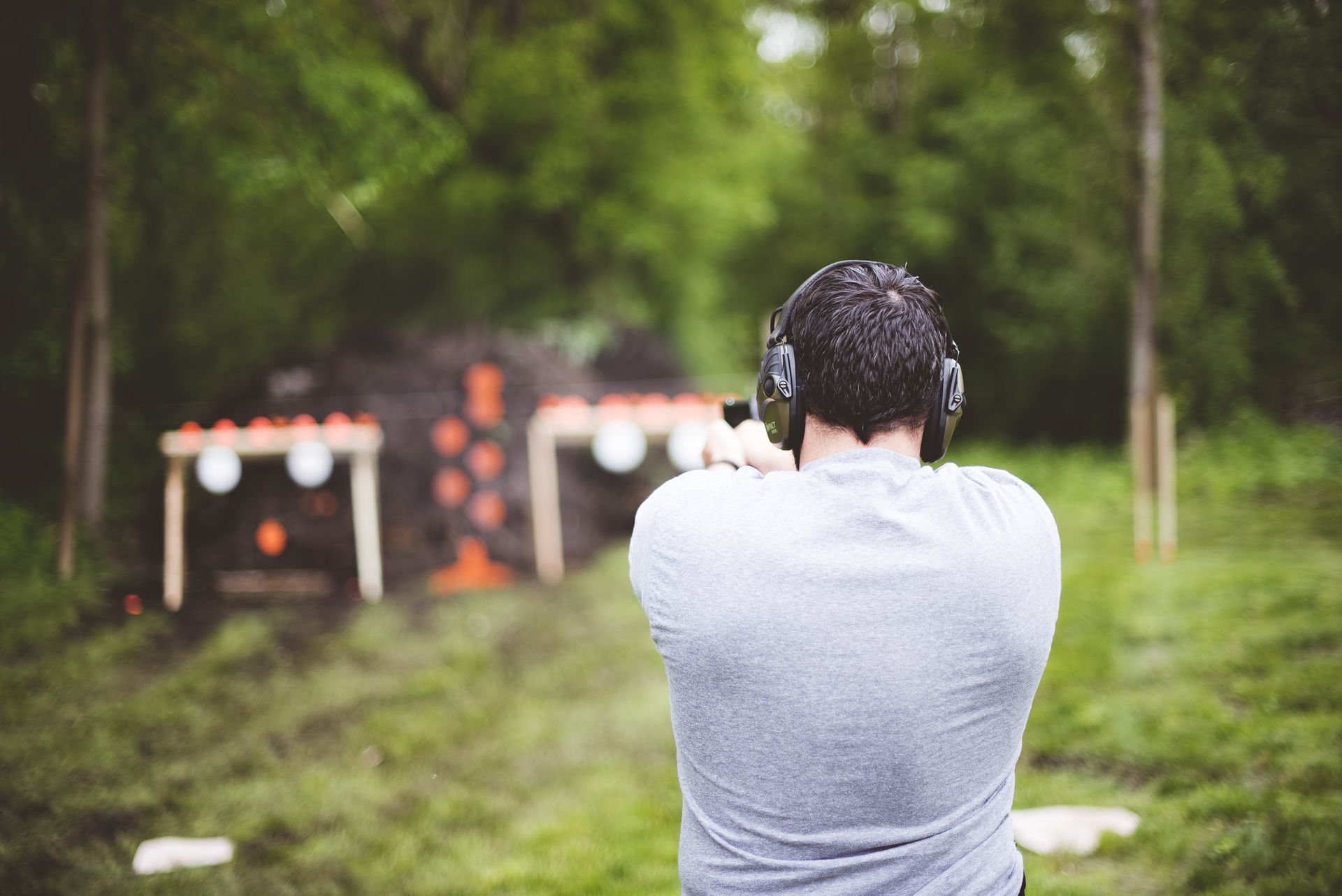 A man practices shooting a pistol in a shooting range while wearing protective headphones