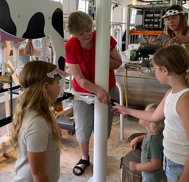 Docent of museum with visitors experiencing the vacuum milker