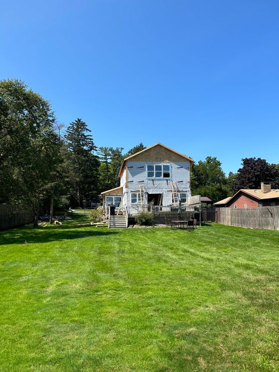 A large house is being built in the middle of a lush green field.