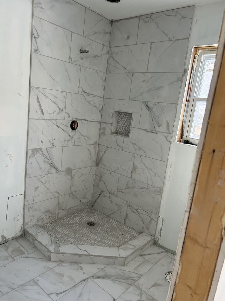 A bathroom with marble tiles and a shower stall.