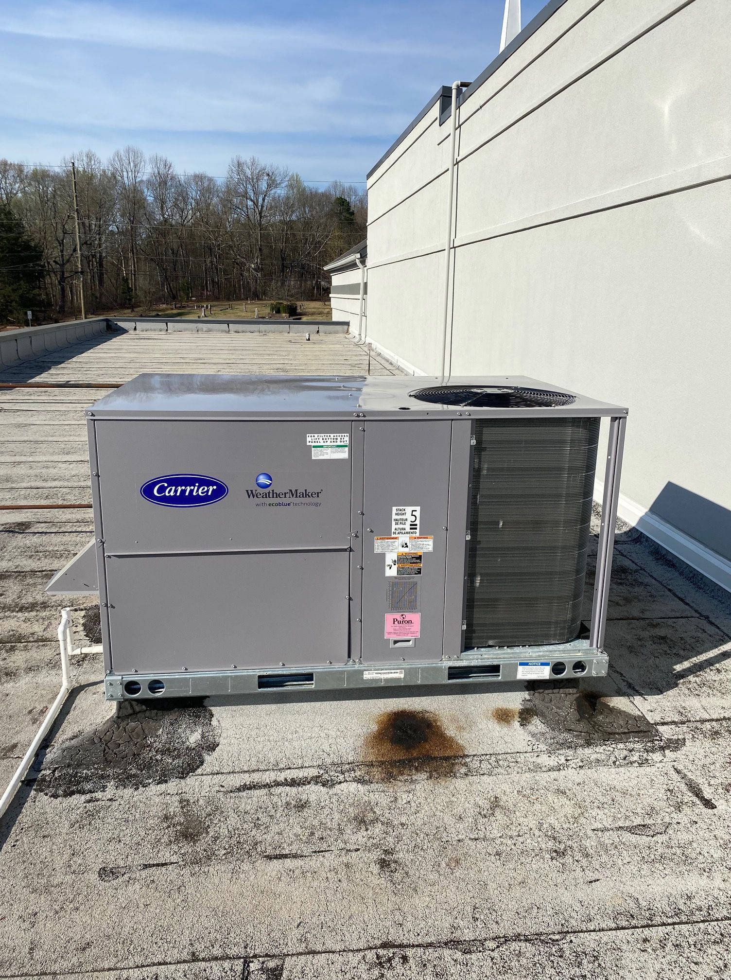 A carrier air conditioner is sitting on the roof of a building.