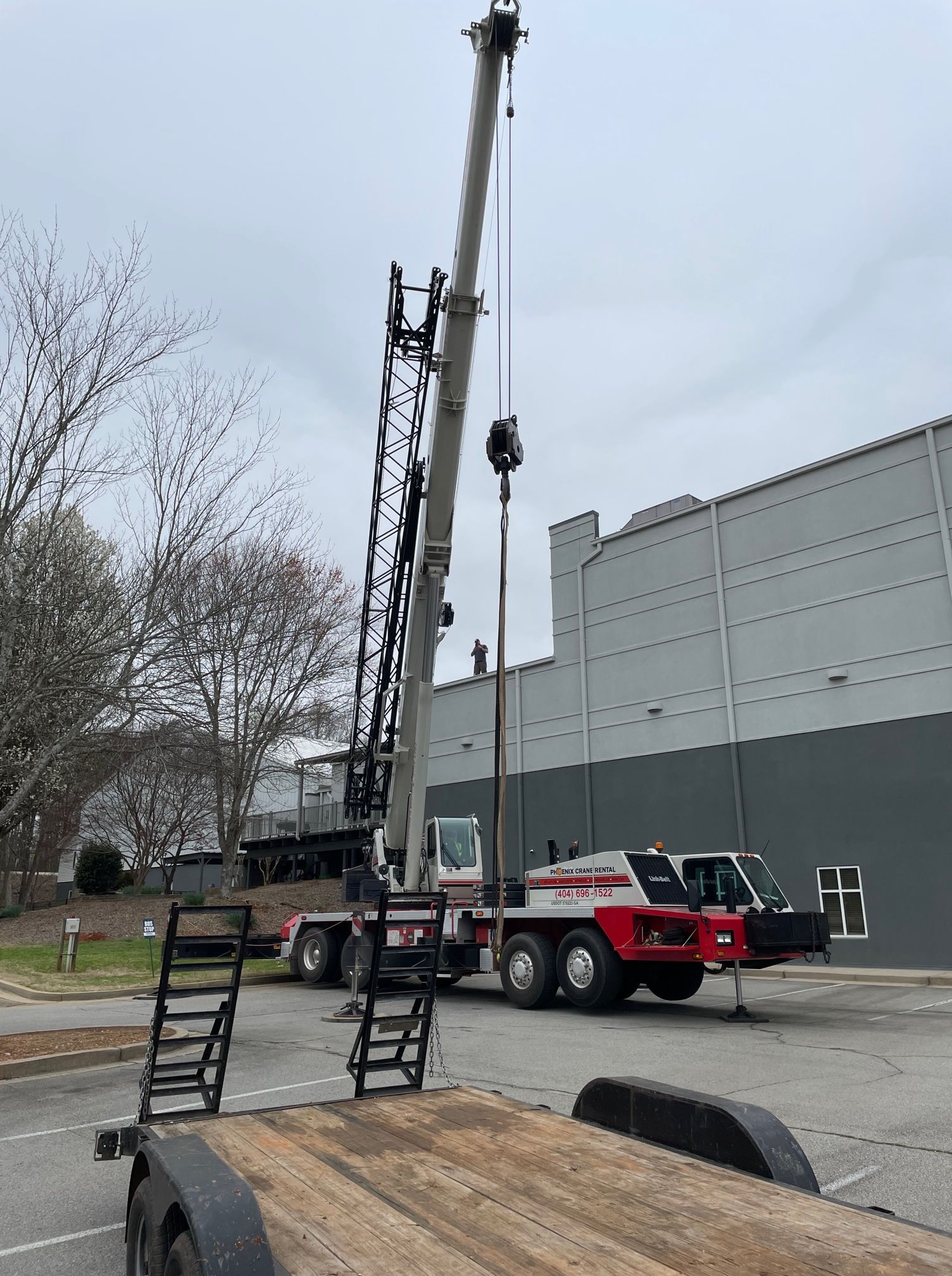 A large crane is sitting on top of a trailer in front of a building.