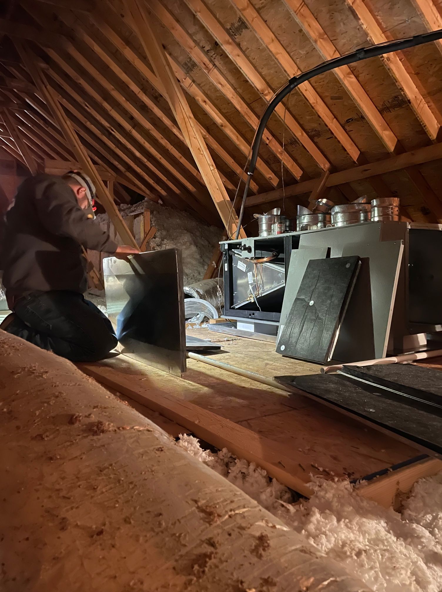 A man is working in an attic with a saw.