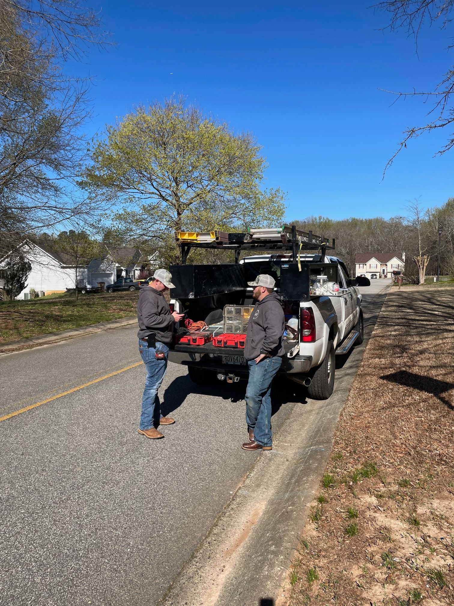 Two men are standing next to a truck on the side of the road.