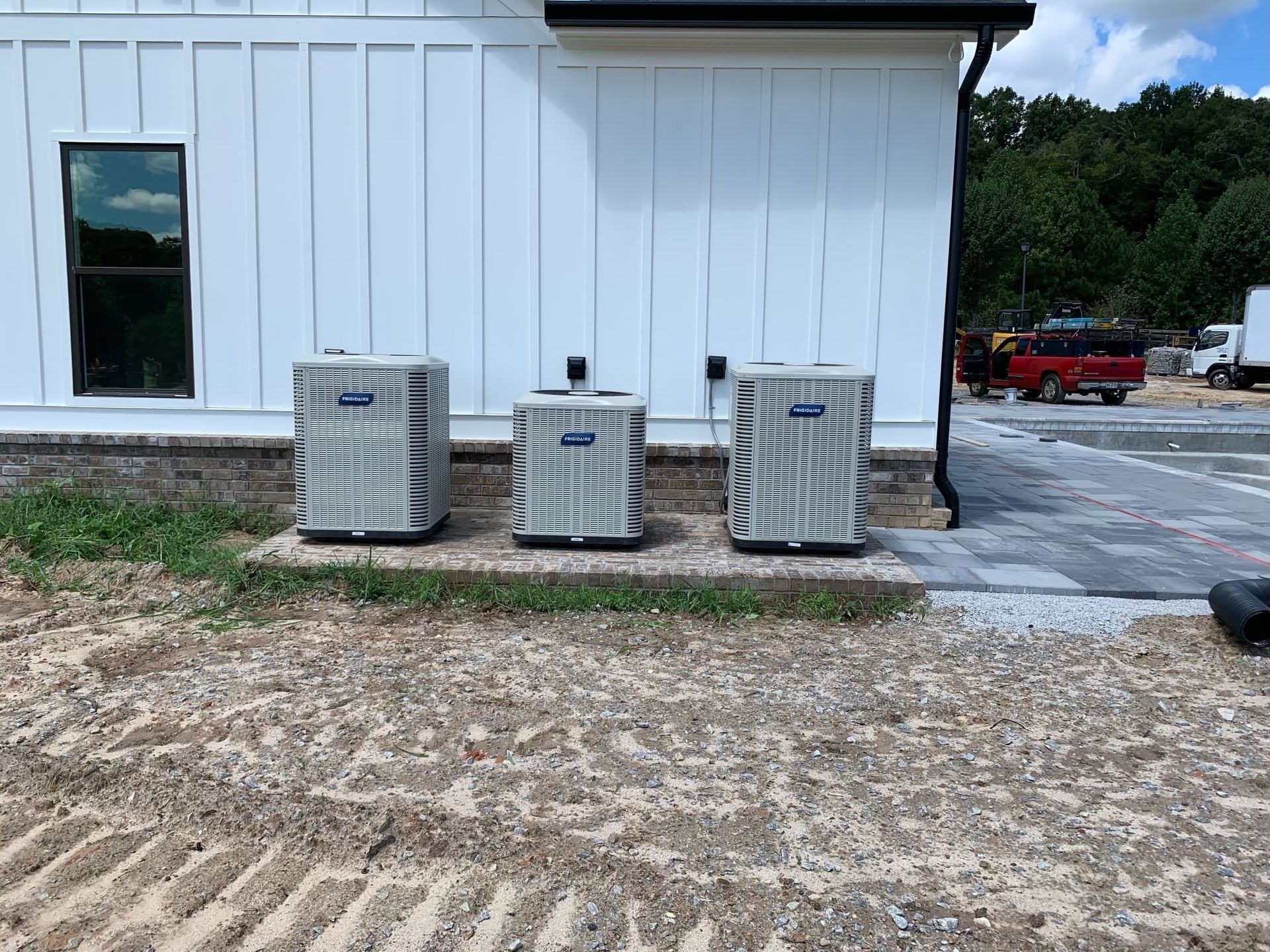 Three air conditioners are sitting in front of a white building.