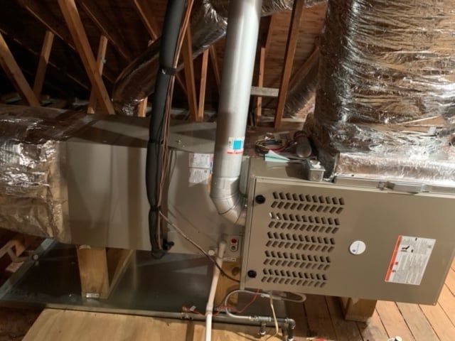 An air conditioner is sitting in the attic of a house.