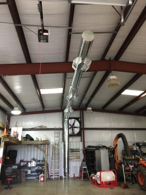 A garage with a tractor and a fan on the ceiling