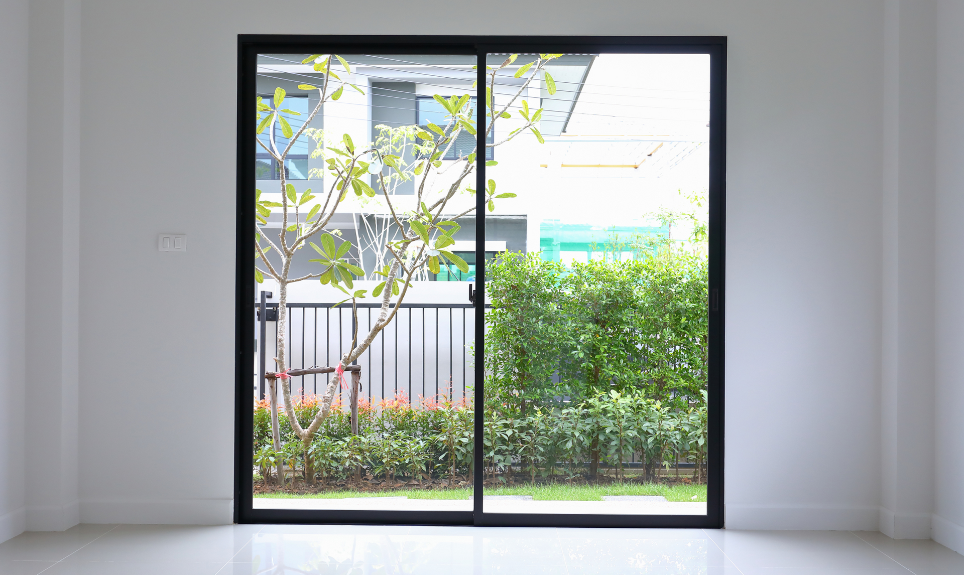 An empty room with a sliding glass door leading to a garden.