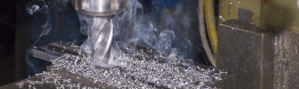 A machine is cutting a piece of metal with smoke coming out of it.