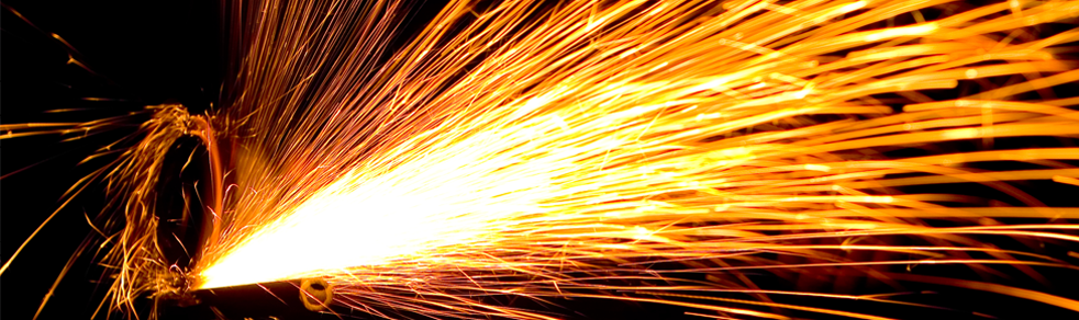 A close up of a machine cutting a piece of metal with sparks coming out of it.