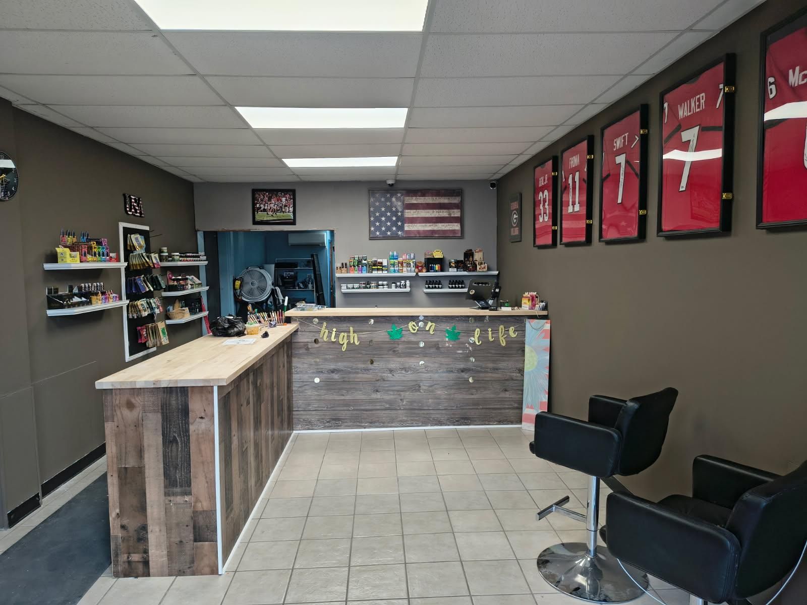 A barber shop with a counter , chairs and jerseys on the wall.