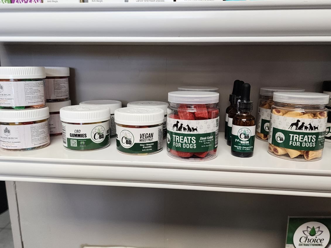 Shelves with various jars of pet treats and oils, labeled with green and white branding.