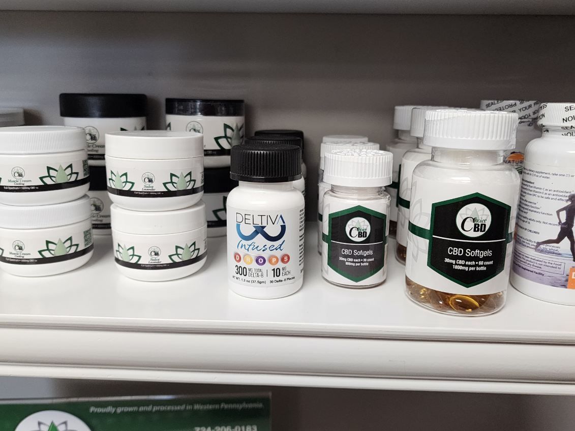 Shelf with various white supplement jars and containers with black and green labels.