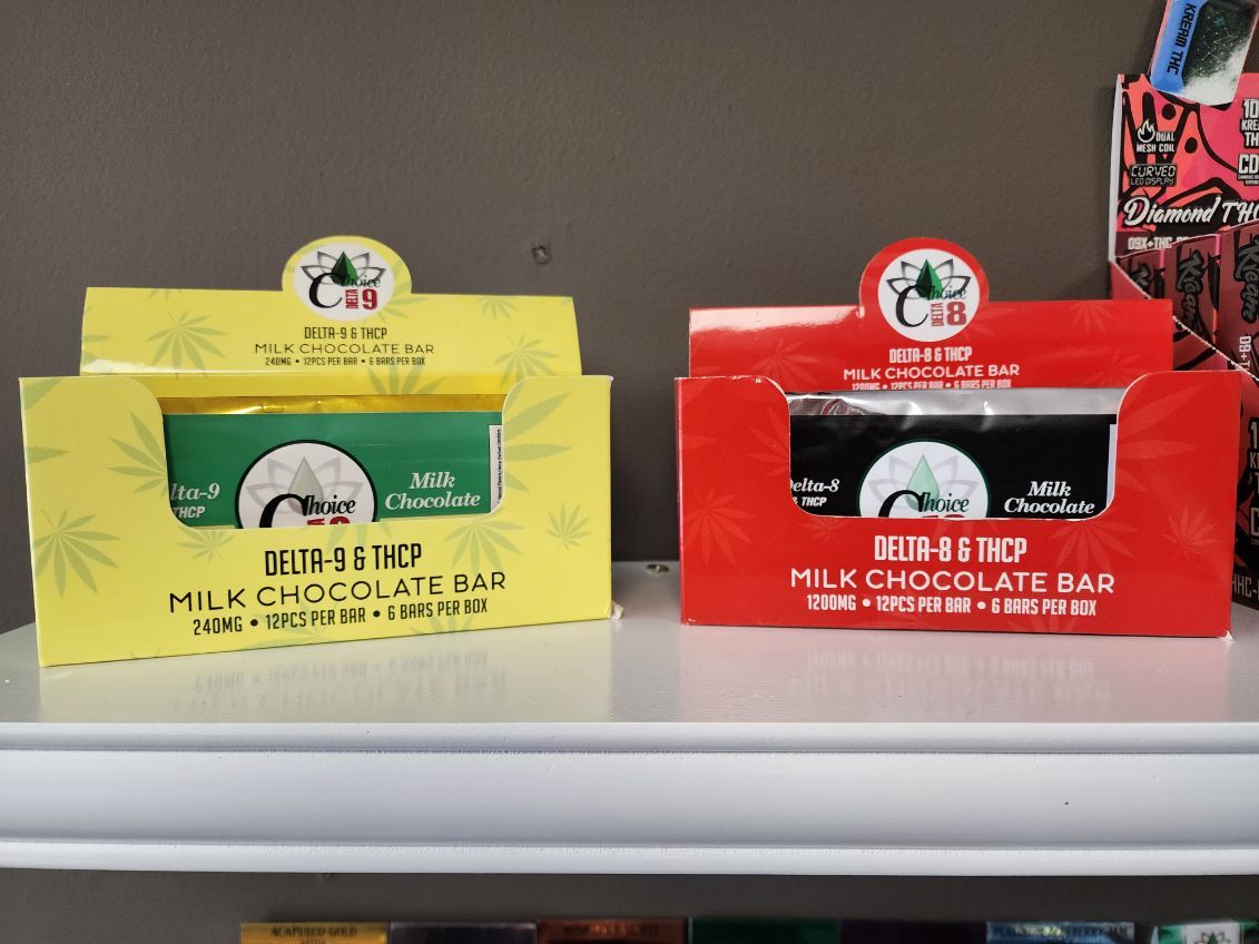 Two boxes of milk chocolate bars, one yellow, one red, with a logo featuring a tree and a person.