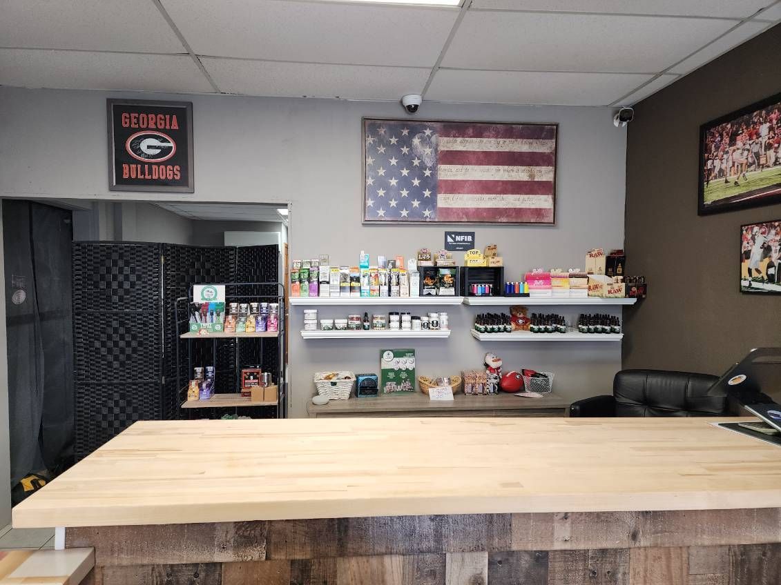 Interior of a retail store with a wood counter, shelves of products, and American flag artwork on the wall.
