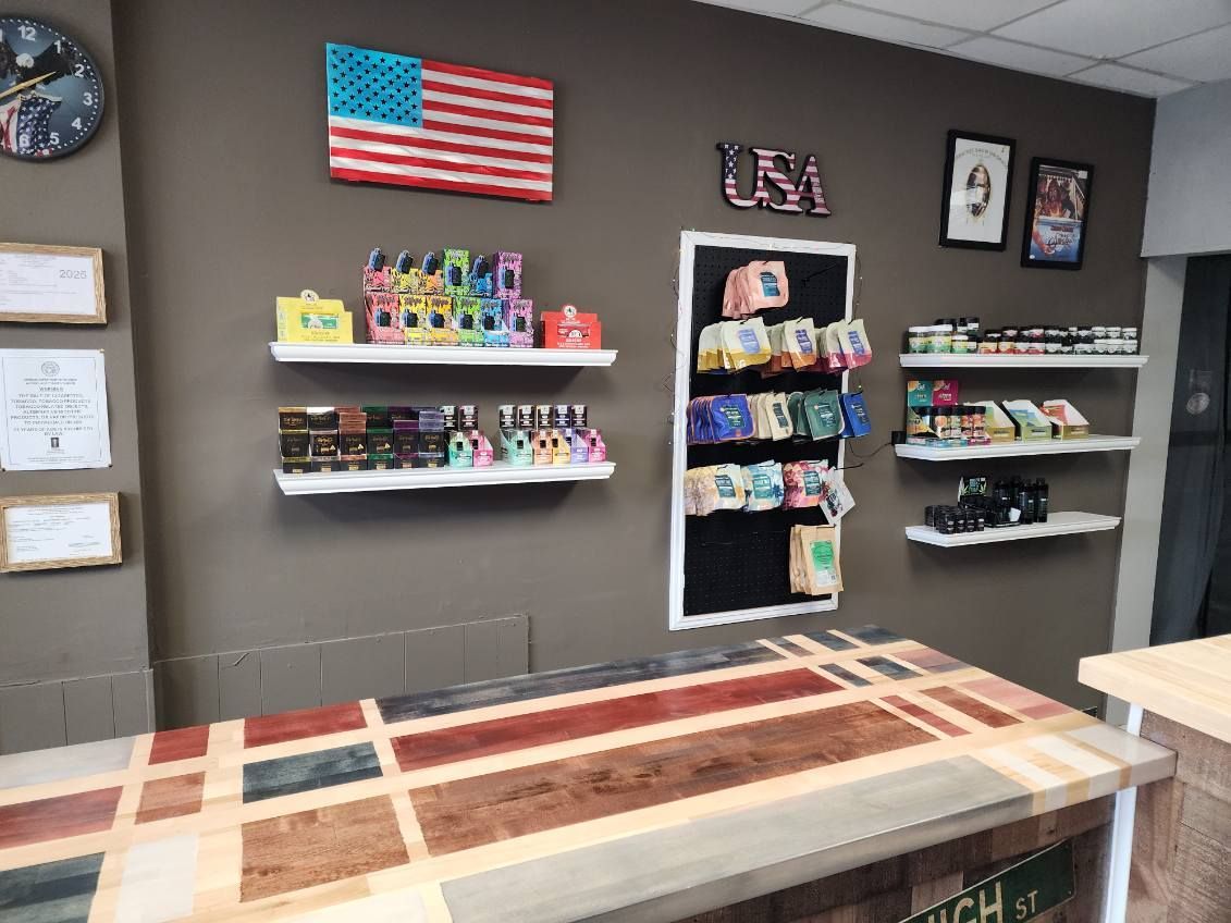 Interior of a vape shop, featuring shelves displaying products, an American flag, and a colorful counter.